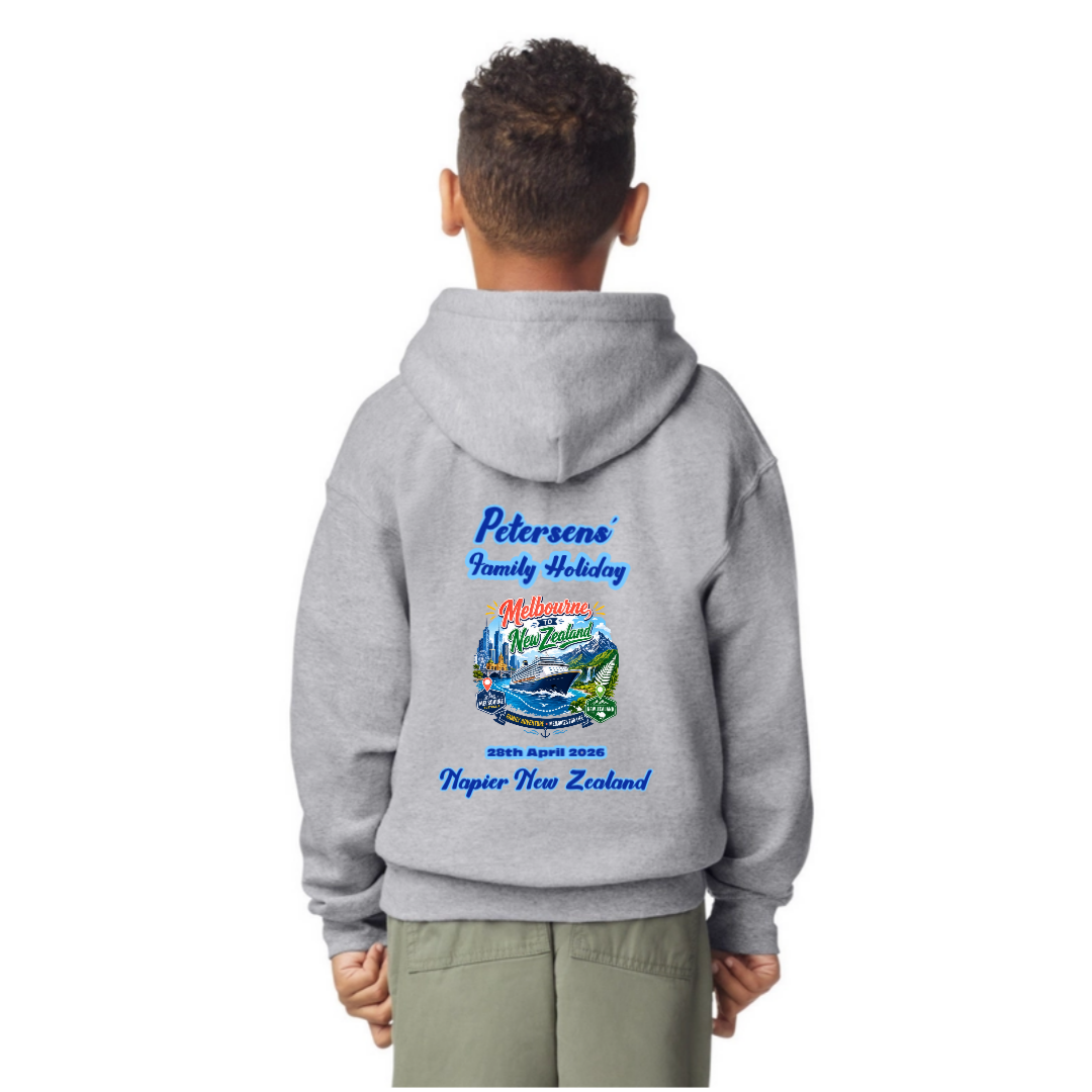 A child viewed from behind wearing a light sports grey pullover Gildan Kids hoodie with a colorful back graphic that reads 'Petersen's Family Holiday' and 'Whanganui, New Zealand' with a scenic illustration. The child is also wearing light olive pants against a plain white background.